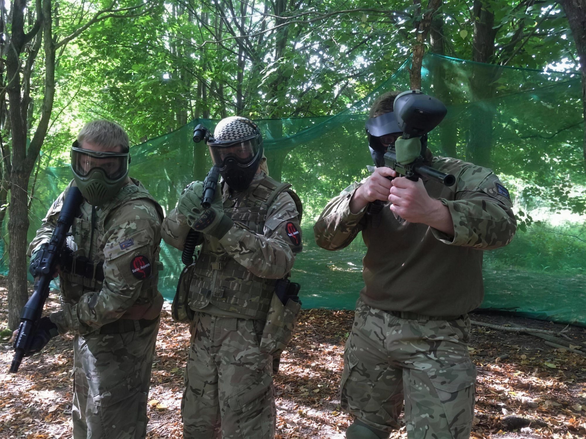 Three players with paintball markers and masks before a session